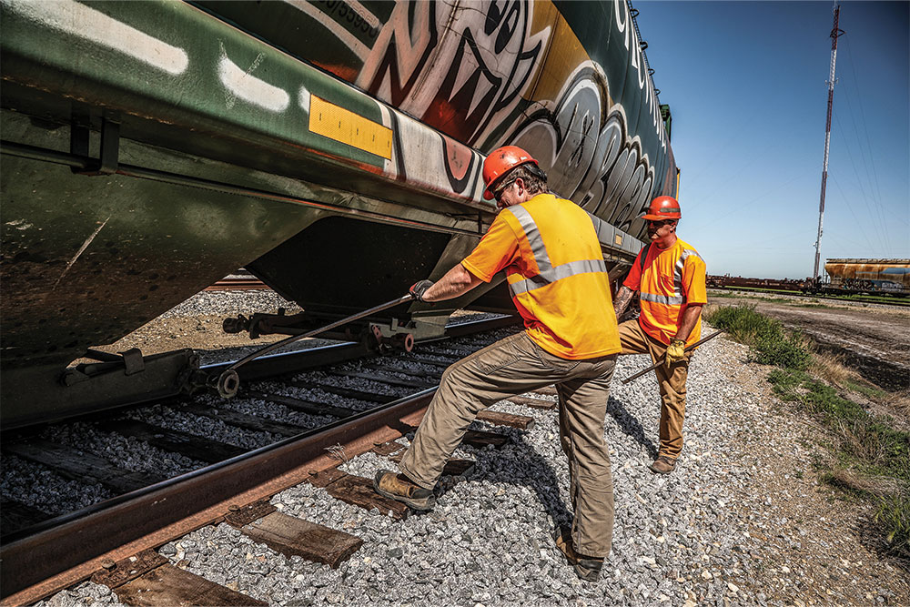 Two Northern Plains Railroad employees performing maintenance on a locomotive.