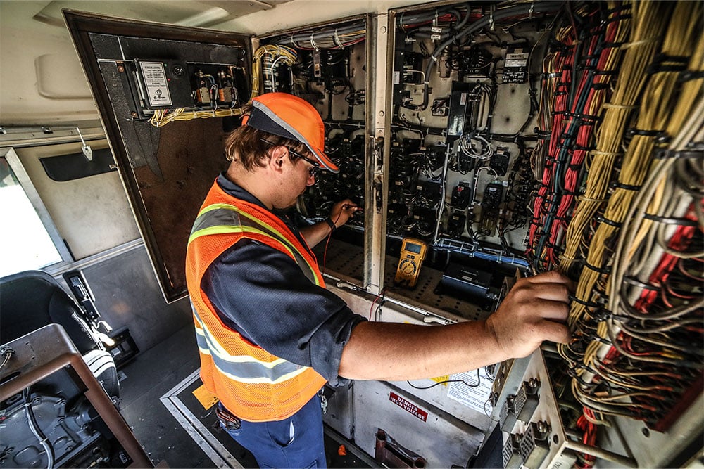 A Northern Plains Railroad employee inspecting inner wires of a locomotive engine.