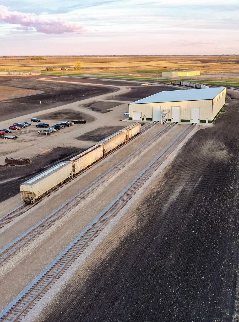 An aerial view of a rail car service and repair warehouse in a rural area