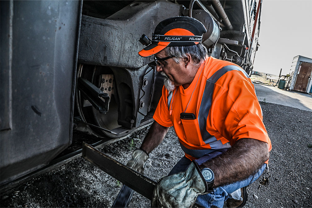 A male Northern Plains Railroad employee performing maintenance on a train car