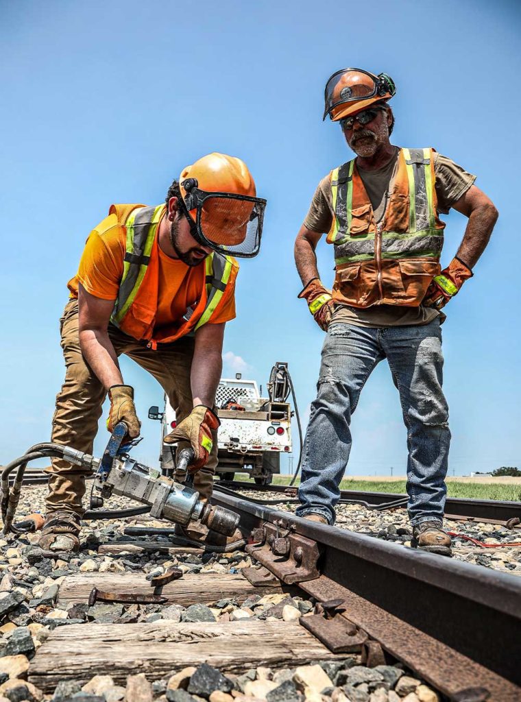 Two male Northern Plains Railroad workers repairing a train track