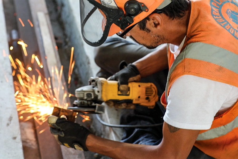 A closeup of a male Northern Plains Railroad employee performing maintenance on a rail track.