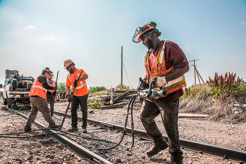 Three male Northern Plains Railroad employees working on a train track.