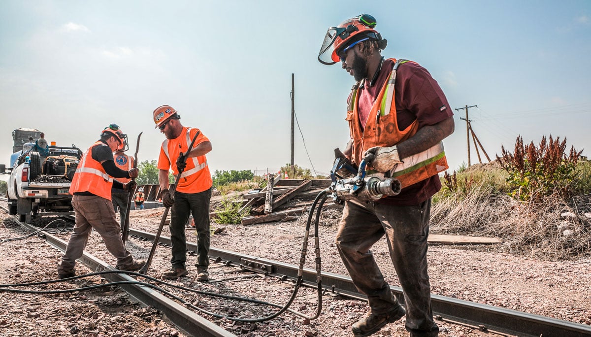 Rail construction crew working to repair a railroad track in the bright sun