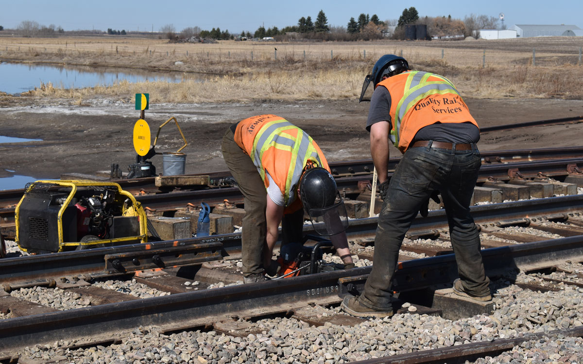 Two rail construction workers working on a track.