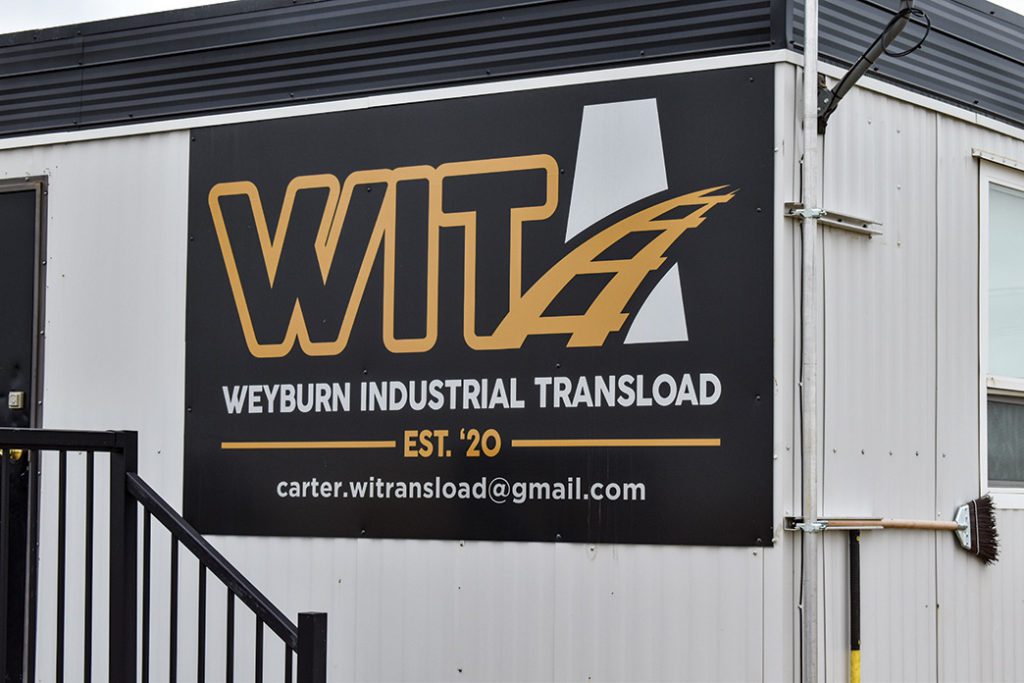 A sign for Weyburn Industrial Transload on the side of a metal building.