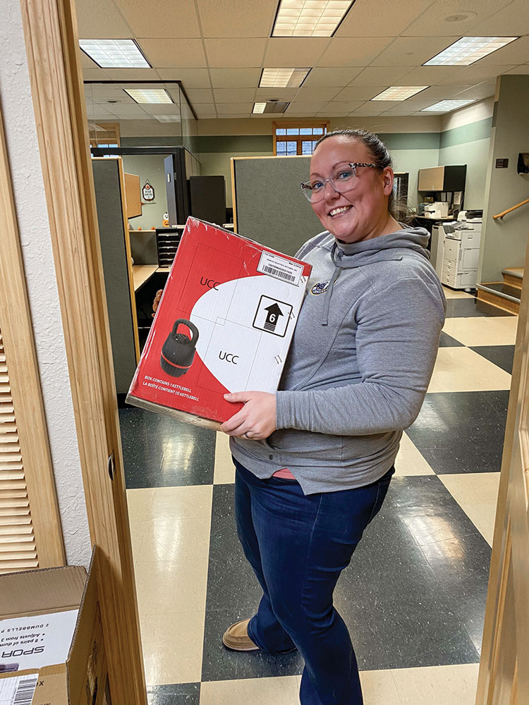 Woman holding a box containing a kettlebell.